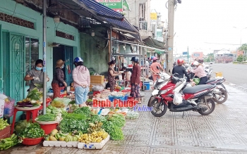 Tiểu thương bày bán la liệt hàng hóa trên vỉa hè quốc lộ 14 đoạn thuộc khu phố Xuân Bình, phường Tân Bình. Ngoài việc đeo khẩu trang, hầu hết người dân không giữ khoảng cách an toàn