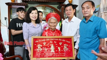 Phó Bí thư Thường trực Tỉnh ủy, Chủ tịch HĐND tỉnh Huỳnh Thị Hằng cùng đoàn công tác đến thăm, trao thư chúc mừng của Chủ tịch nước, bức khánh cùng vải lụa cho cụ Nguyễn Thị Cháu tròn 100 tuổi ở xã Đức Liễu, huyện Bù Đăng - Ảnh: Phạm Quang