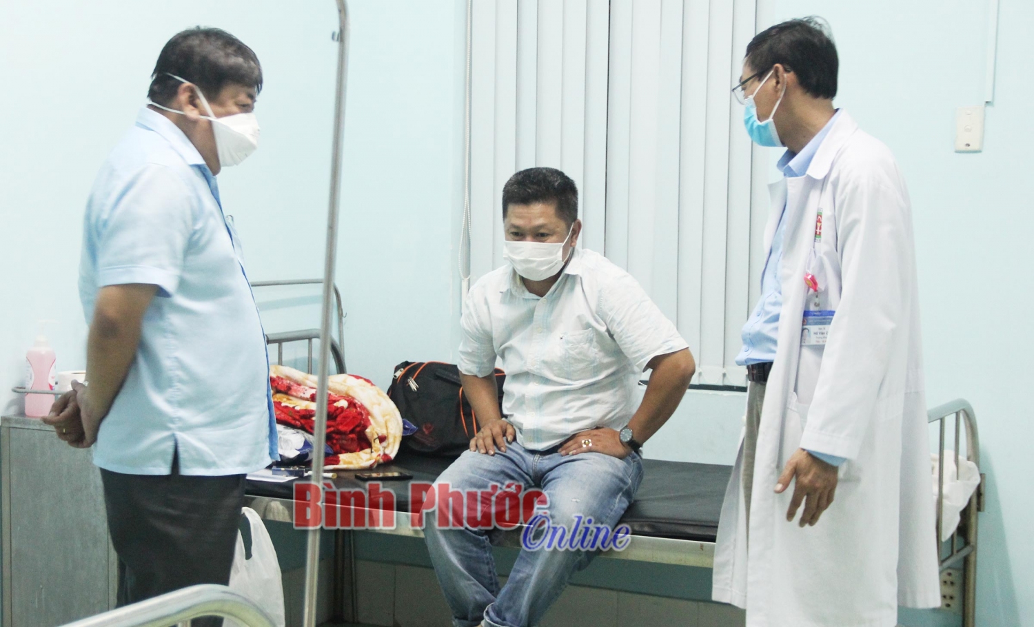 Bác sĩ Quách Ái Đức, Giám đốc Sở Y tế (trái) và các bác sĩ tại Trung tâm Y tế huyện Đồng Phú thăm hỏi, động viên anh T. yên tâm thực hiện việc cách ly
